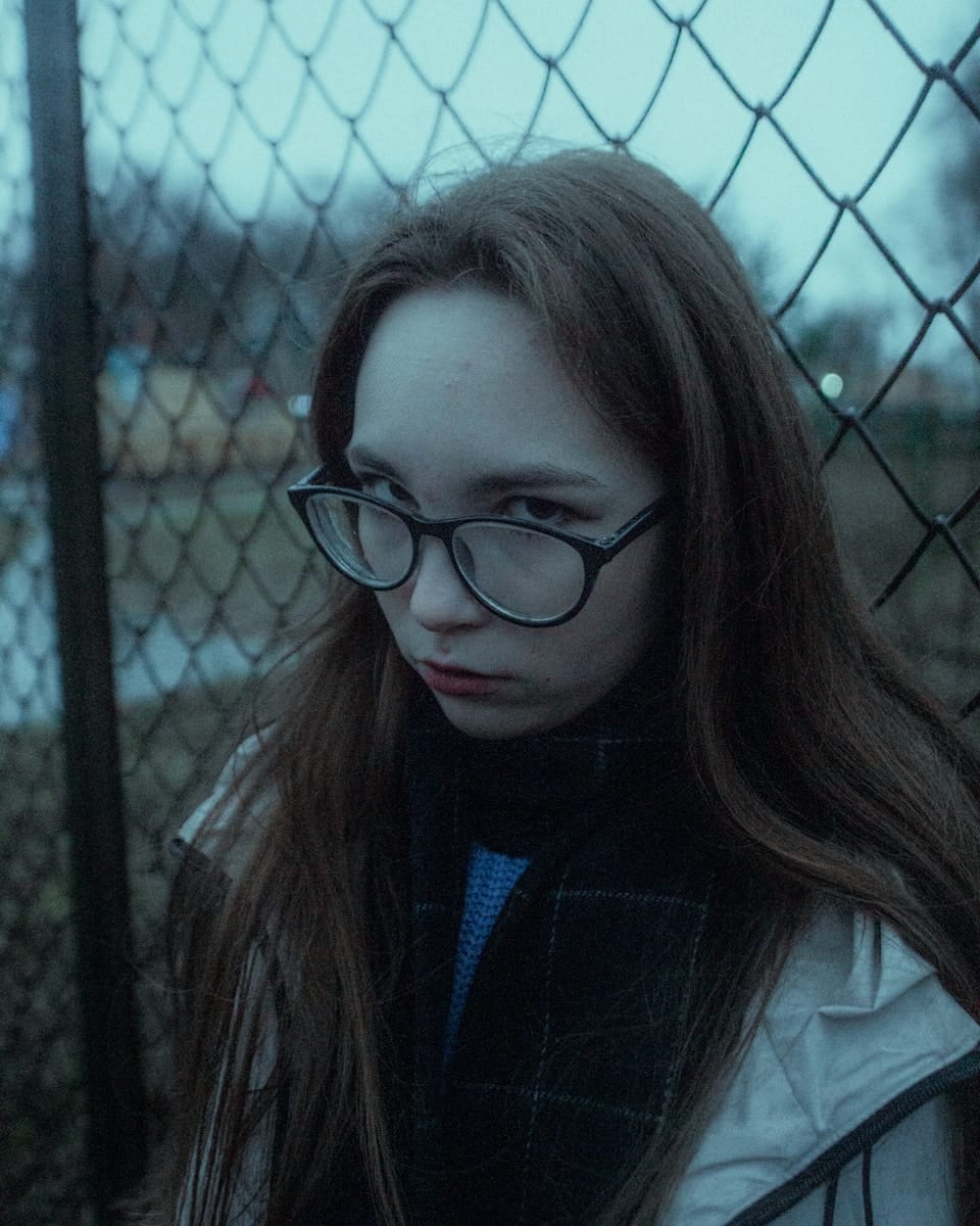 Young woman with glasses behind a fence