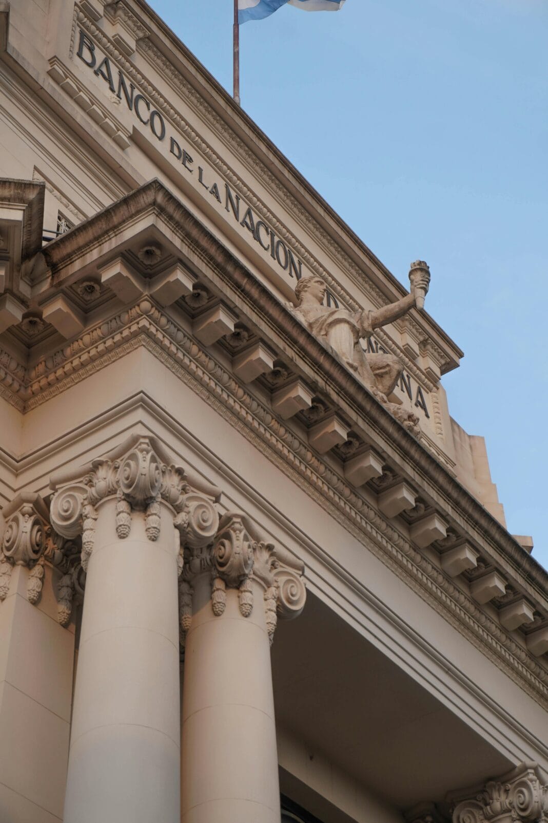 Fachada neoclássica do Banco de la Nación Argentina com colunas ornamentadas sob céu azul.