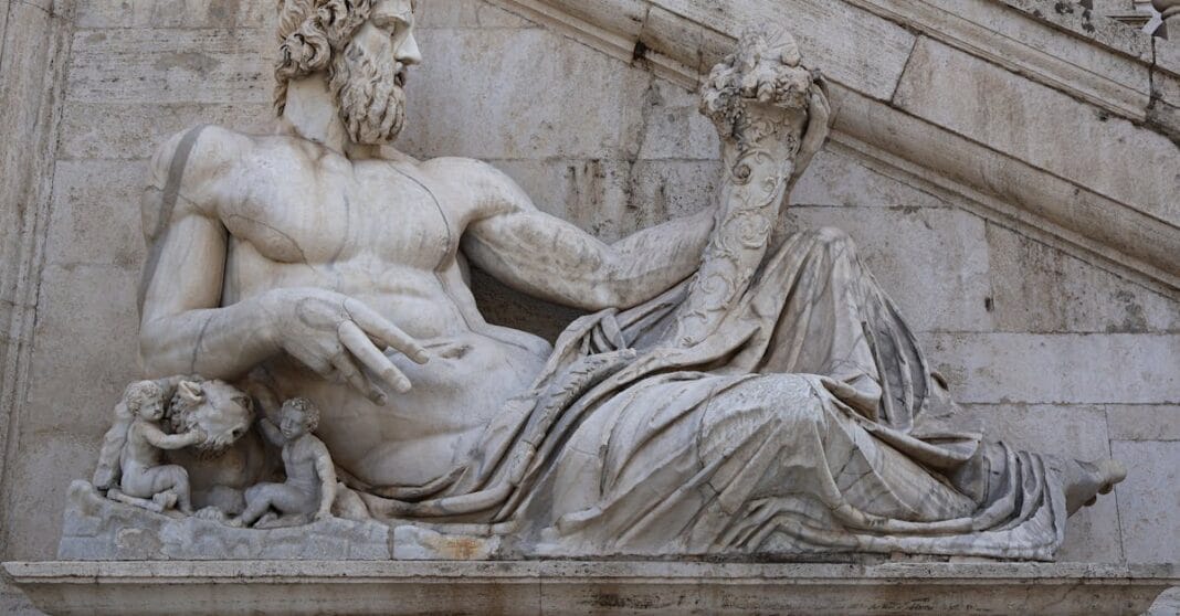 Estátua romana em mármore representando um deus reclinado, fotografada em Roma.