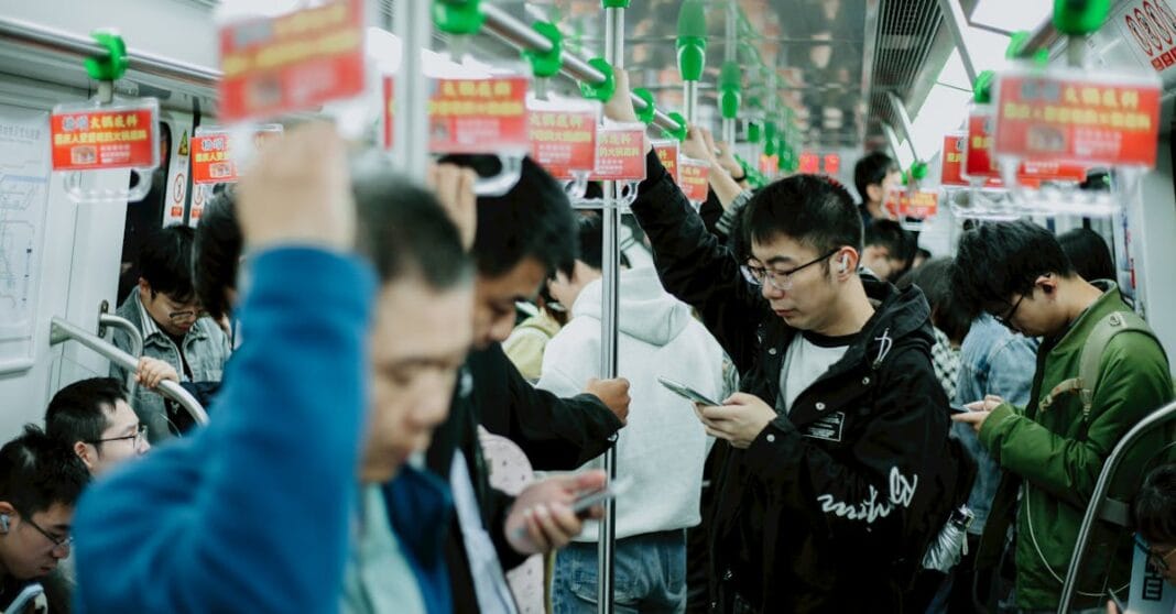 Homens e mulheres usam telemóveis num metro lotado na China, durante uma viagem em hora de ponta.