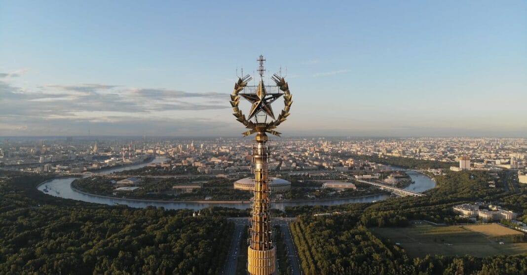 Vista aérea de Moscovo com o emblema dourado soviético em primeiro plano, simbolizando poder e vigilância
