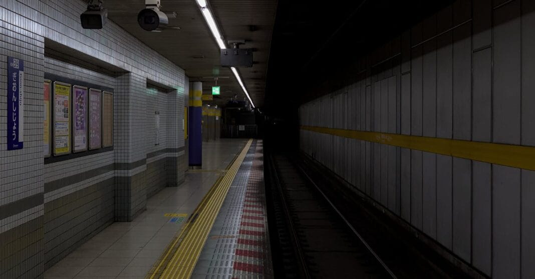 Estação de metro vazia com iluminação ténue e linha amarela junto à via.