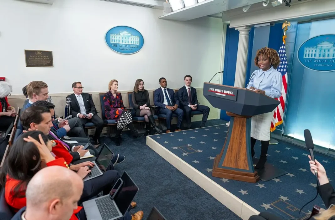Karine Jean-Pierre fala ao púlpito durante o briefing diário na Sala de Imprensa da Casa Branca, com jornalistas sentados em frente.