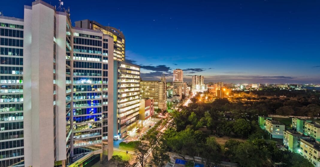 Vista aérea nocturna de Dar es Salaam com arranha-céus iluminados e estrada principal cheia de luzes