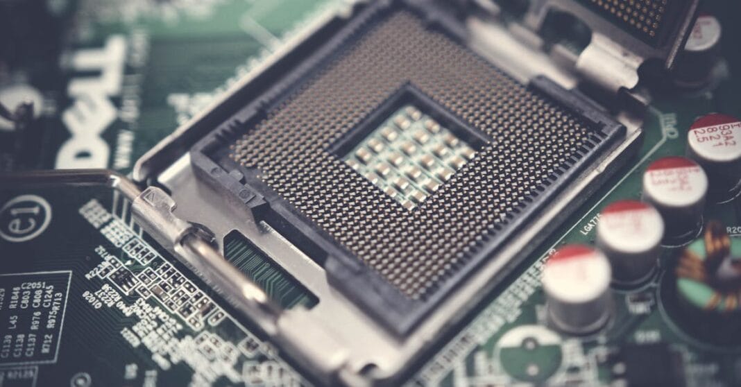 Close-up de um processador CPU montado numa placa de circuito com componentes eletrónicos visíveis, ilustrando a arquitetura de semicondutores