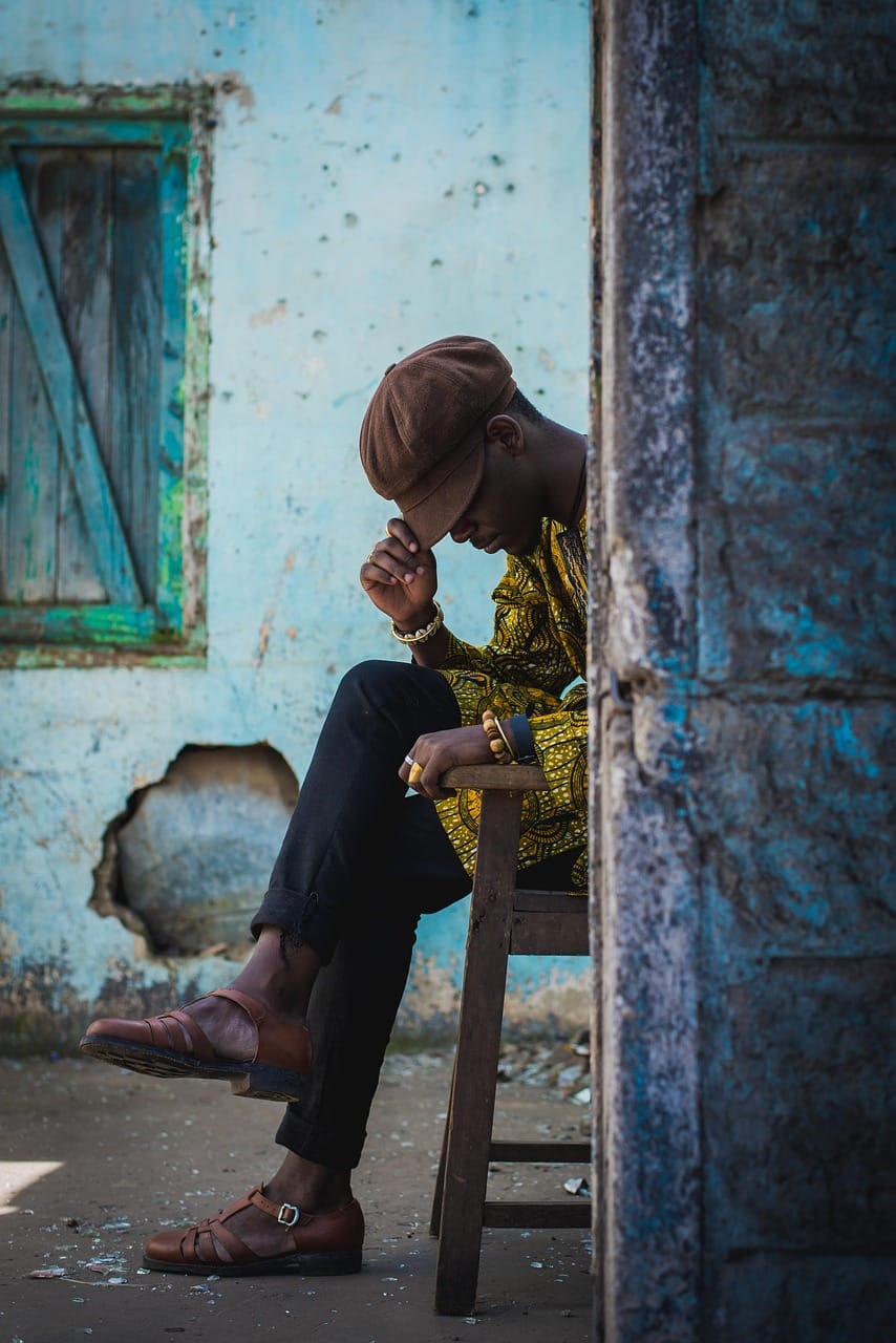 Homem africano sentado em edifício deteriorado, simbolizando a vulnerabilidade económica explorada por esquemas de recrutamento militar russo em África