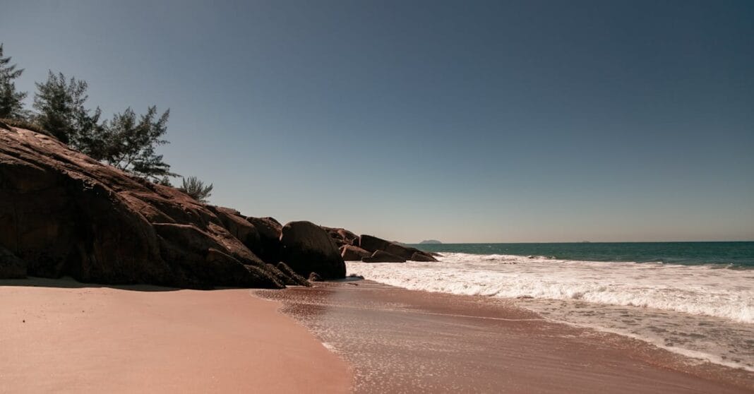 Peaceful beach scene in Florianópolis, Brazil with calm waves and a clear blue sky.