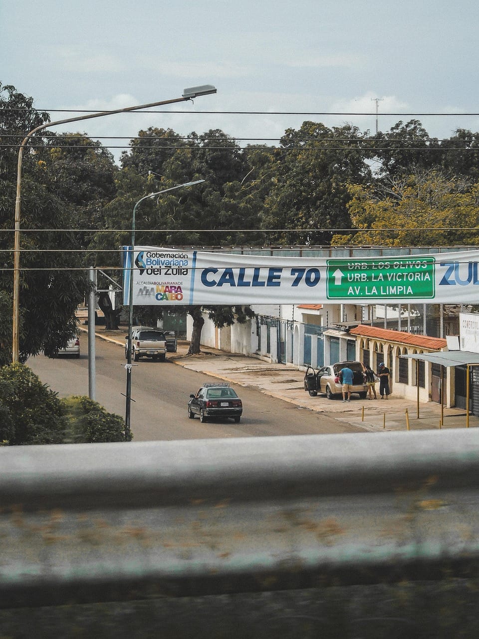Placa “Calle 70” numa rua urbana, com carros e árvores ao fundo