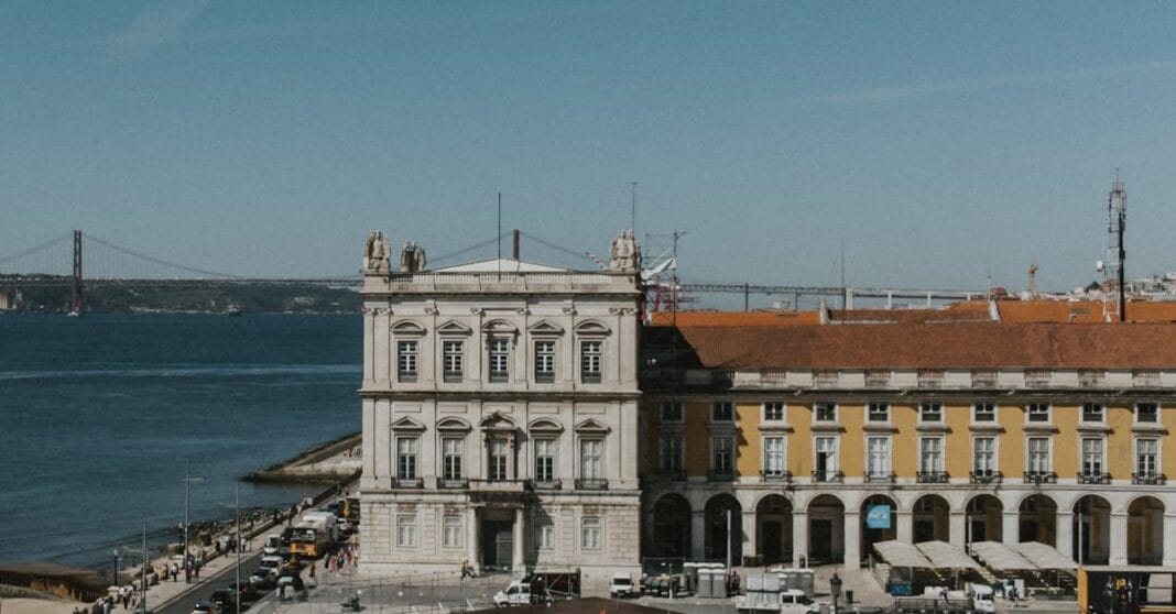 Vista aérea da Praça do Comércio, em Lisboa, com o rio Tejo ao fundo num dia claro.