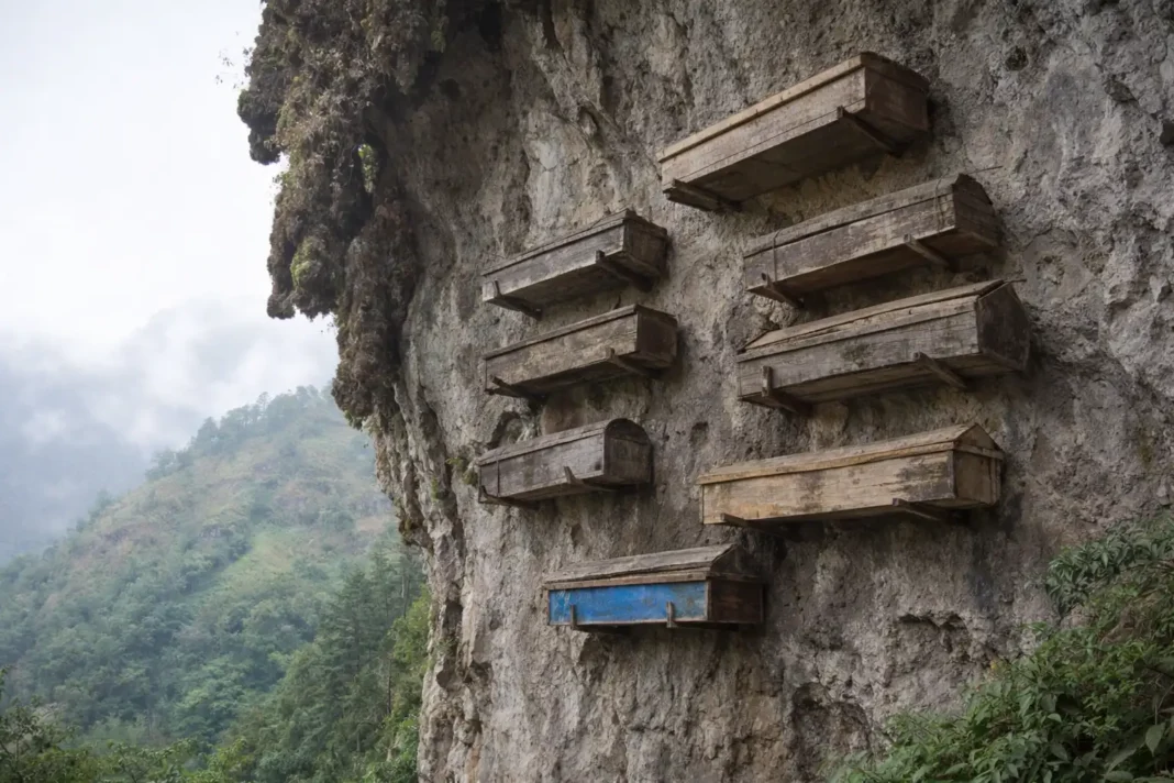 Caixões de madeira fixados numa falésia rochosa sobre um vale verde e enevoado no sul da China.