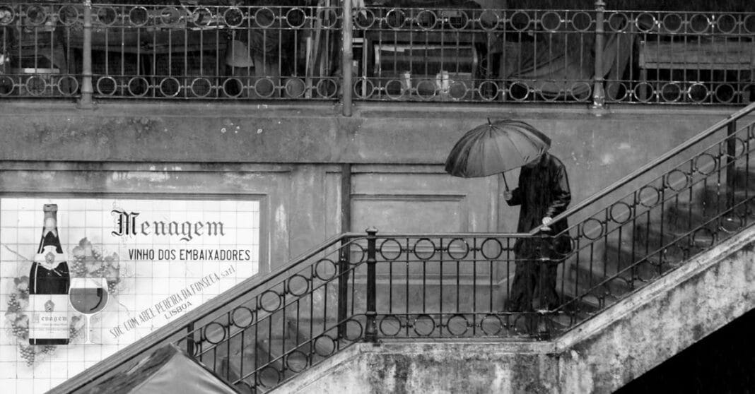Pessoa com guarda-chuva a descer escadas à chuva em Lisboa.