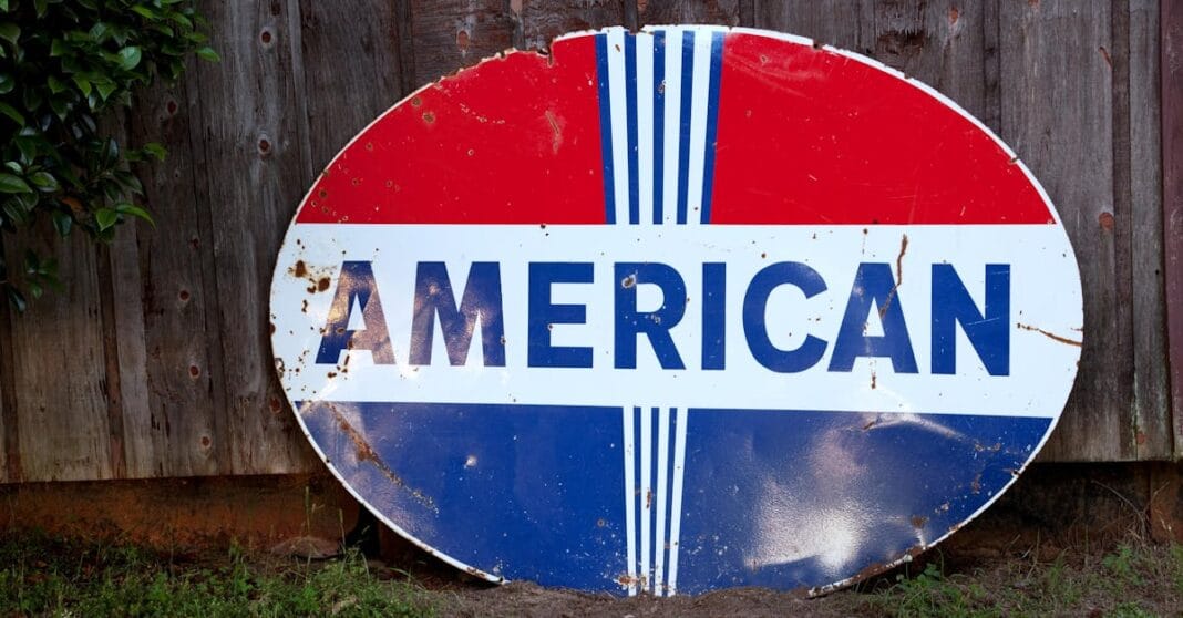 Placa antiga com a palavra “American”, evocando identidade e poder dos Estados Unidos.