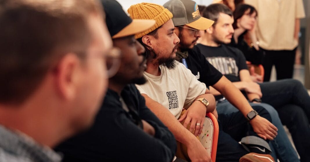 Pessoas sentadas em fila a assistir a uma sessão pública numa sala.