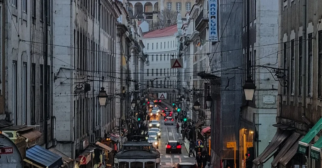 Vista aérea de uma rua comercial de Lisboa ao entardecer, com trânsito e transeuntes, símbolo da transformação urbana que eliminou a marginalidade produtiva da cidade