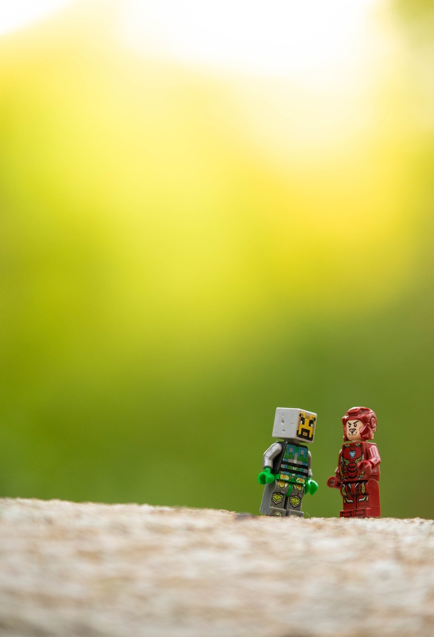 Duas pequenas figuras de brinquedo sobre uma superfície clara, com fundo verde desfocado.