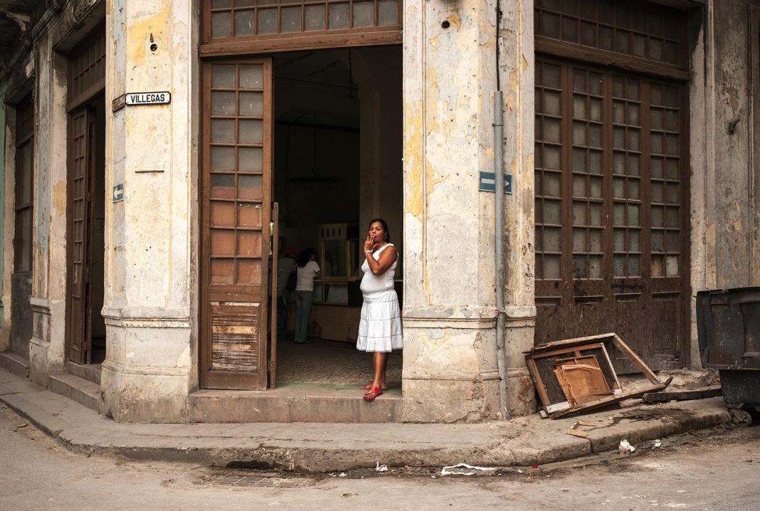 Mulher à entrada de um edifício degradado numa rua de Havana, em Cuba.