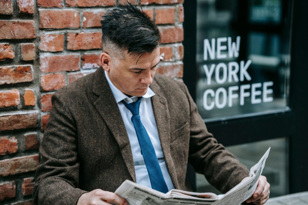 Leitura de um jornal à porta do café