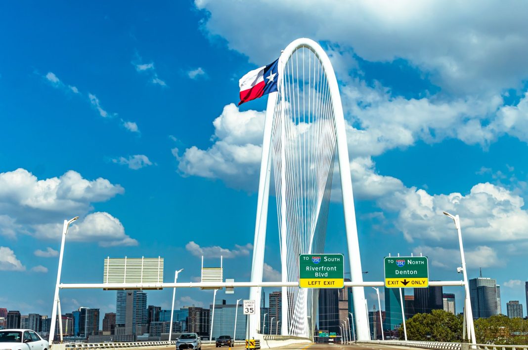 Bandeira do Texas diante do arco branco da Ponte Margaret Hunt Hill, em Dallas.