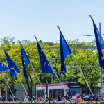 Bandeiras da União Europeia hasteadas em frente ao Parlamento Europeu, em Bruxelas, simbolizando a política europeia de defesa e a autonomia estratégica.