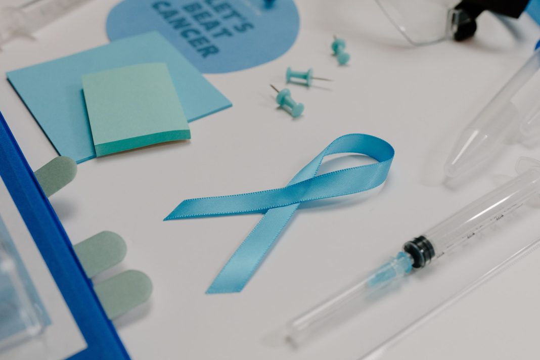 Laço azul junto de material médico, associado à consciencialização para o cancro.
