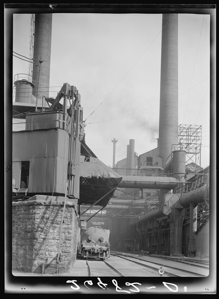 Vista de um complexo siderúrgico industrial em Pittsburgh, com várias chaminés altas e edifícios fabris típicos da produção de aço do século XX.