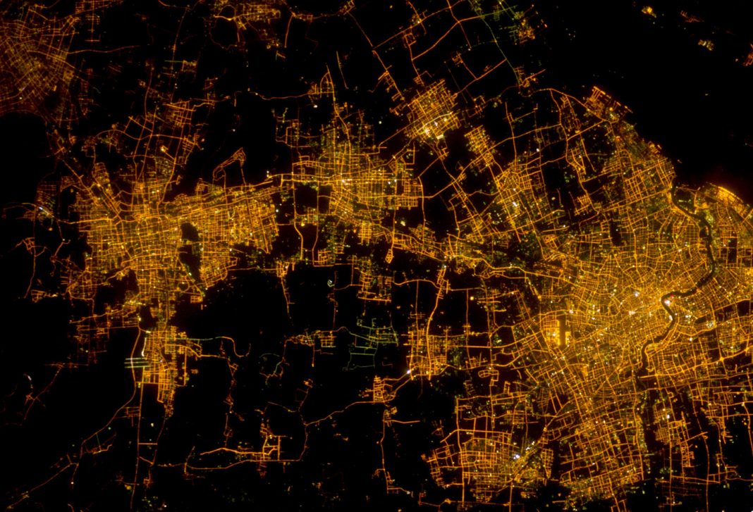 Vista nocturna de Xangai, com os arranha-céus iluminados do distrito de Pudong junto ao rio, fotografada a partir da Estação Espacial Internacional.
