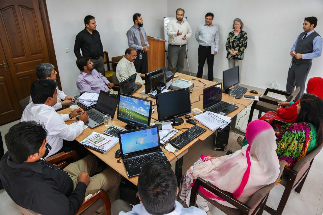 Participantes numa formação em informática trabalham com computadores portáteis numa sala