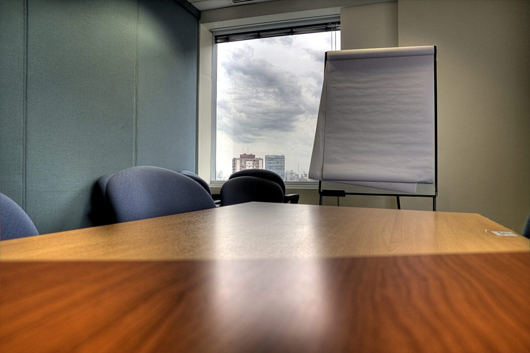 Sala de reuniões com mesa e quadro, imagem ilustrativa de decisões de coinvestimento