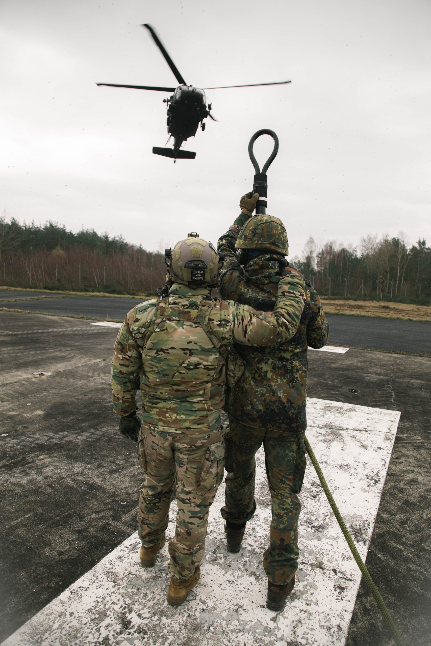 Militar americano orienta um soldado alemão na preparação de uma carga suspensa para um helicóptero UH-60 Black Hawk
