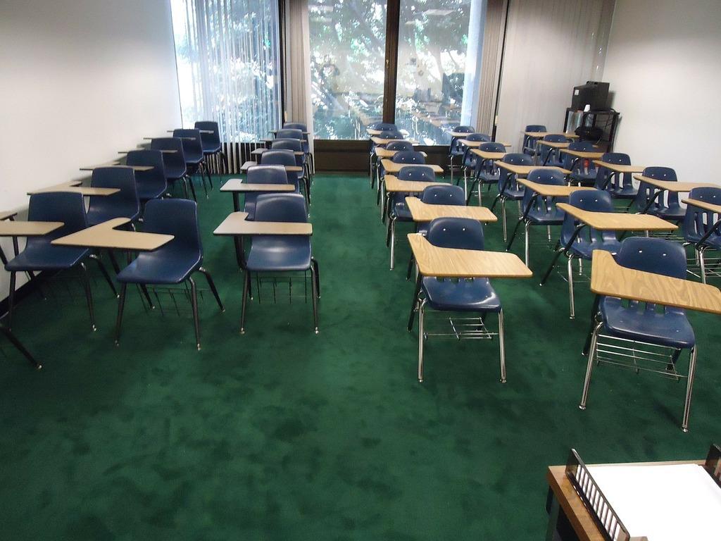 Mesas e cadeiras numa sala de aula vazia, contexto da falta de professores