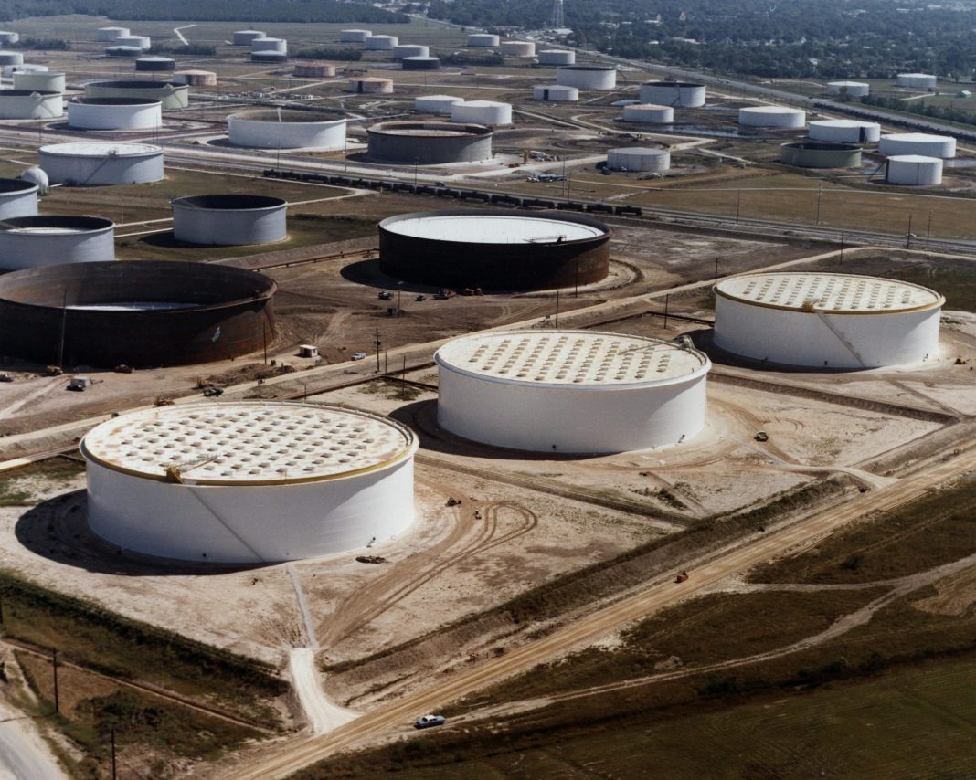 Vista aérea de reservatórios cilíndricos de petróleo e tubagens num terminal em Nederland, no Texas