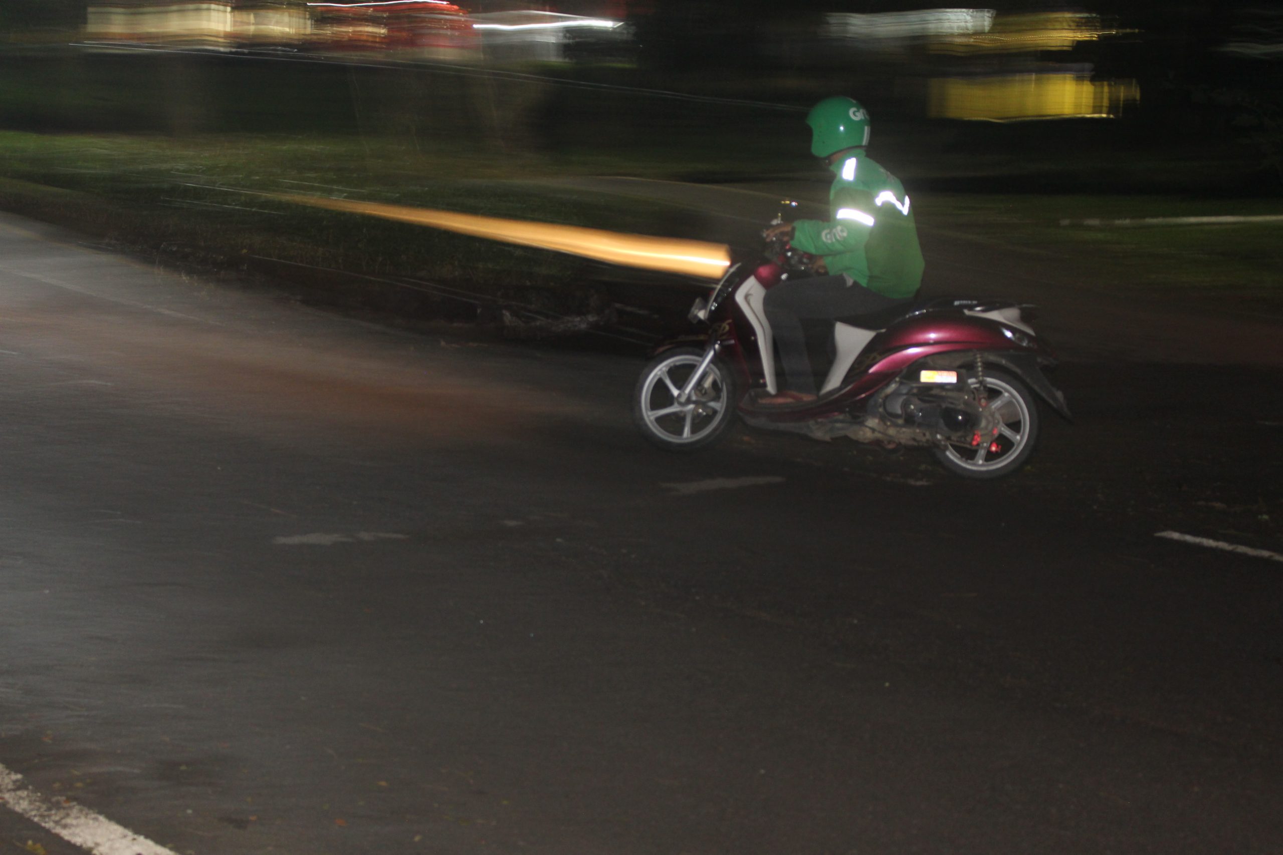 Condutor de transporte por aplicação num veículo de duas rodas, à noite