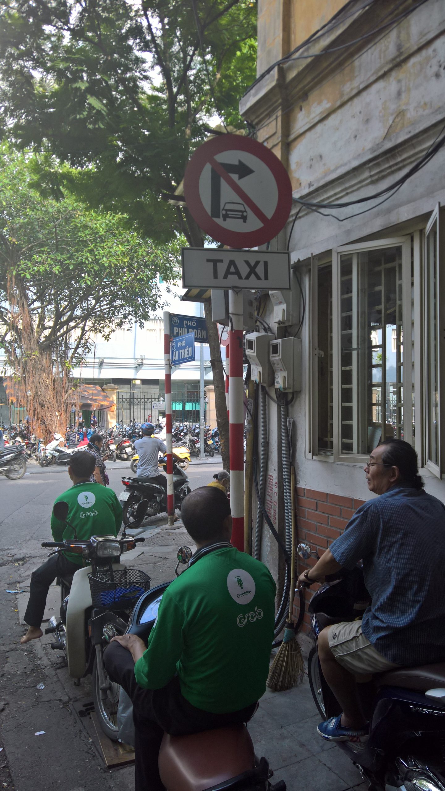 Condutores GrabBike junto de um sinal de trânsito em Hanói, no Vietname