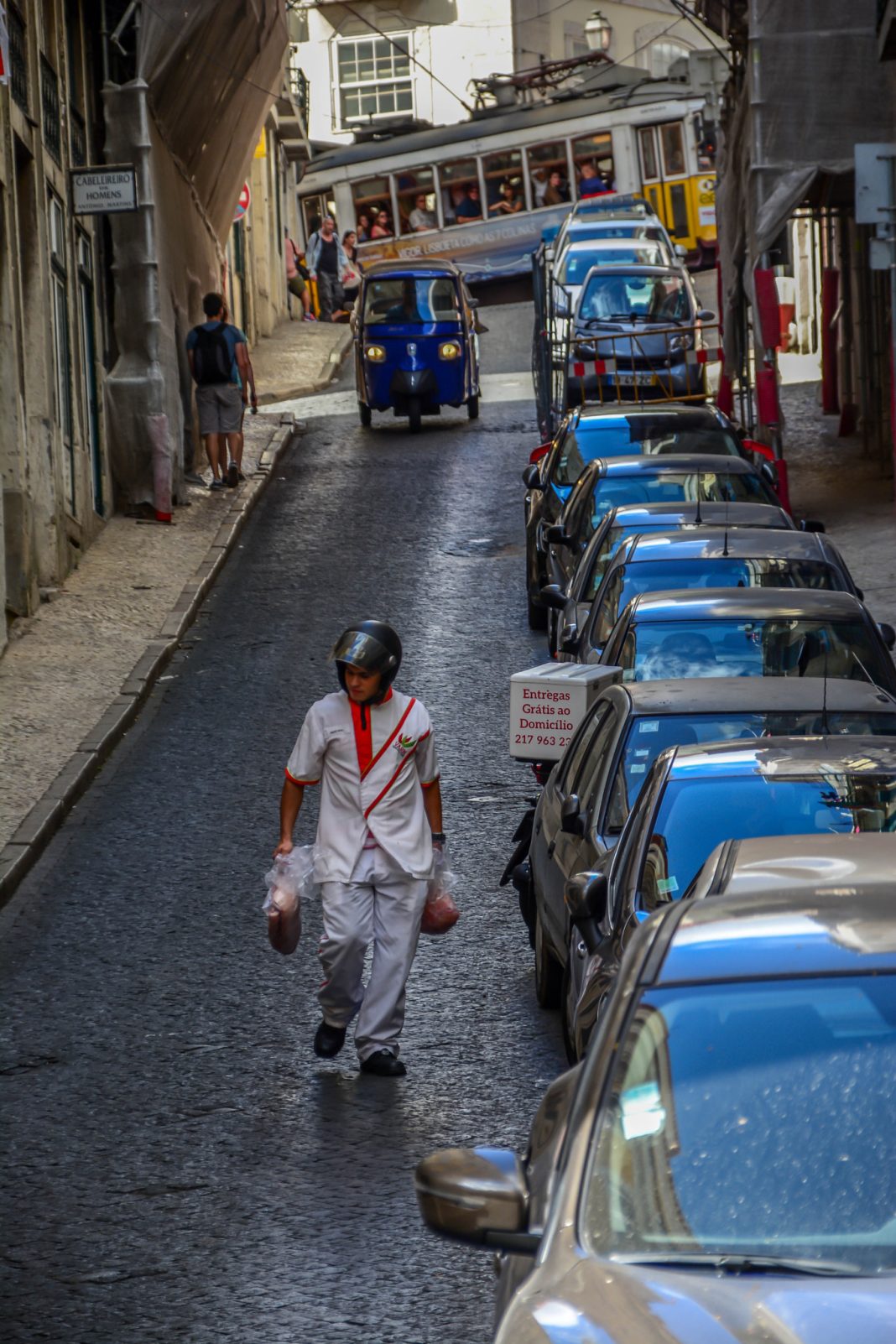 Homem transporta caixas numa rua de Lisboa, junto de um veículo